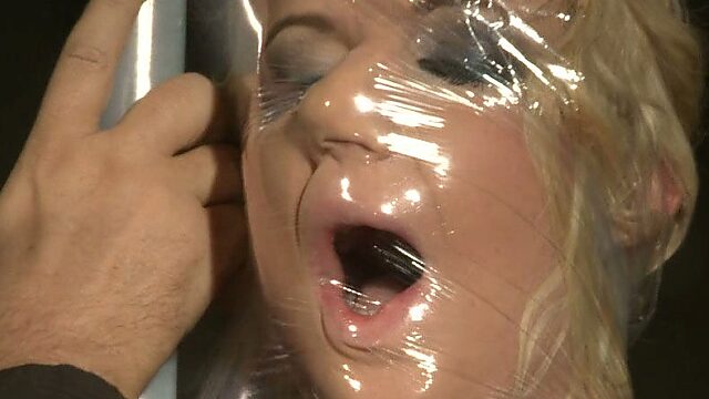 Slutty blondie is covered in a clear wrap in hot BDSM scene