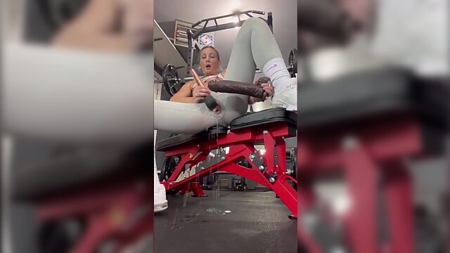 Blonde MILF plays with her pussy using a giant dildo at the gym